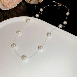 Collier de perles blanches élégant avec fil de pêche transparent sur une assiette blanche.