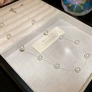 Collier élégant en perles blanches flottantes sur fil invisible dans un écrin à bijoux