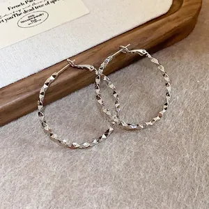 Detailed close-up of high-end geometric rhombic faceted hoop earrings with silver needle