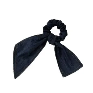 Elegant blue denim scrunchie with a bow-knot design shown on a white background