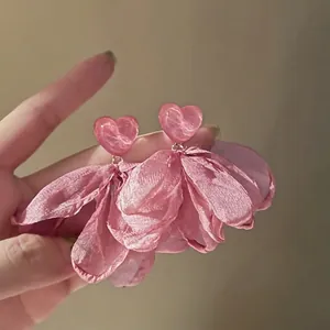 Macro detail of pink fabric petal earrings with heart-shaped resin studs