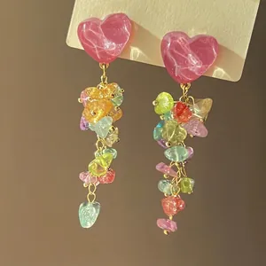 Detailed macro view of colorful stone tassel earrings with pink heart-shaped studs.
