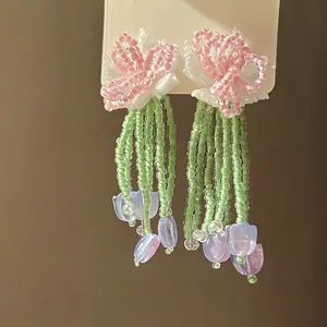 Detailed view of hand-beaded flower tassel earrings with pink and green accents.