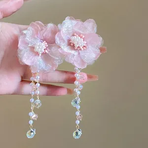 Close-up detail of pink fabric flower tassel earrings featuring pearls and crystal drops.