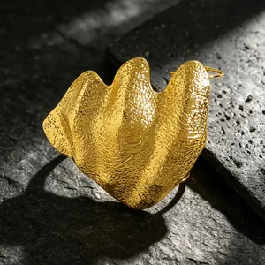 Close-up macro detail of an artistic irregular crumpled gold joint ring on textured stone background