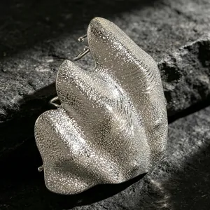 Detailed view of an artistic irregular pleated silver knuckle ring with a textured finish