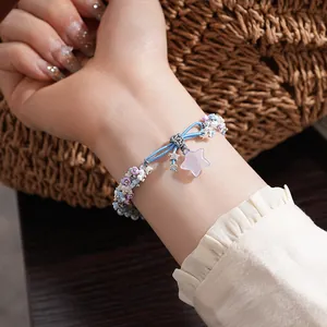Detailed macro view of a resin woven bracelet with star and flower pendants on a wrist.