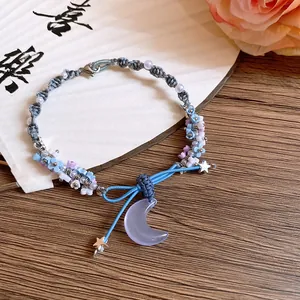 Detailed view of a braided bracelet with resin flowers and a purple moon pendant.
