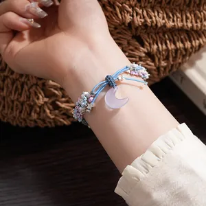 Detailed close-up showing a resin flower and moon charm woven bracelet on a wrist