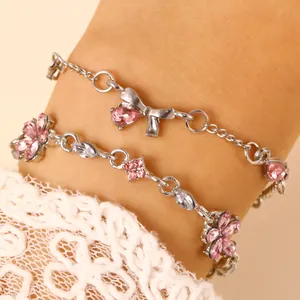 Close-up view of elegant silver-tone bracelets featuring pink flower and bow zircon charms