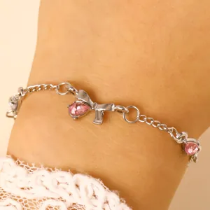 Macro detail of silver bow bracelet with sparkling pink teardrop stones on wrist