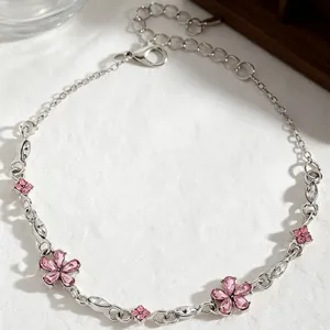 Detailed view of elegant silver bracelet featuring pink rhinestone flowers and zircon inlay