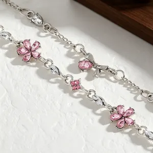 Close-up of elegant silver-toned bracelet with pink zircon flowers and bow details