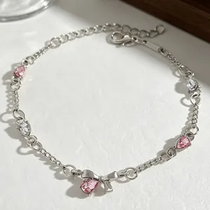 Macro shot of a silver bow bracelet featuring pink and white pear-cut zircon crystals.