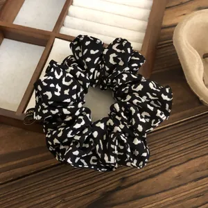Elegant black and white leopard print satin scrunchie hair tie for women.