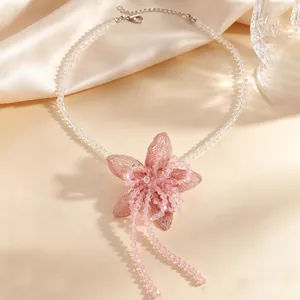 Detailed shot of a sweet pink fabric flower pendant on a clear beaded necklace with tassels
