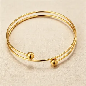Close-up of minimalist gold-plated stainless steel double-loop bracelet with steel beads.