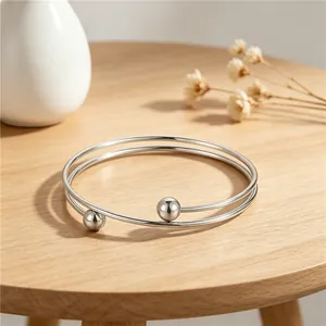 Close-up of minimalist double wrap stainless steel bangle with polished silver beads