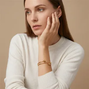 Detailed view of a minimalist gold stainless steel double-loop bracelet on a model wrist