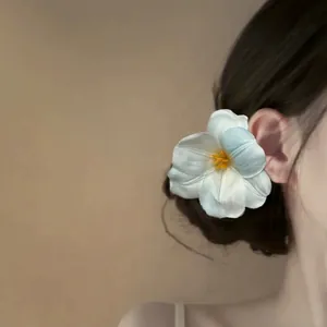 Elegant white fabric flower hair clip with blue gradient petals on model