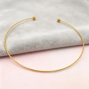 Detailed view of minimalist gold C-shaped titanium steel choker on soft velvet