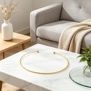 Minimalist gold C-shaped titanium steel torque necklace displayed on a luxury marble table