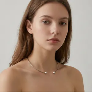 Detailed view of a minimalist silver-toned titanium steel C-shaped choker worn on model's neck.
