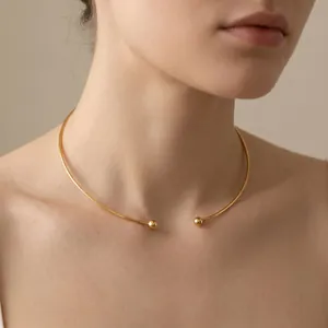 Close-up of a minimalist gold C-shaped titanium steel choker necklace on a model