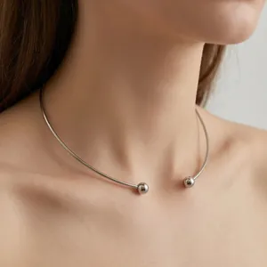 Close-up of minimalist silver titanium steel C-shaped open collar necklace on neck
