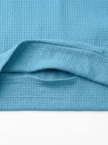 Close-up of blue waffle knit fabric texture and hem stitching on men's polo shirt