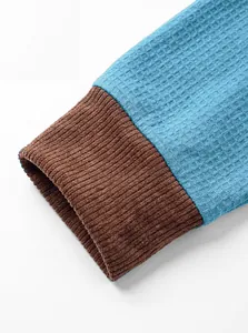 Close-up of blue waffle knit fabric and brown ribbed cuff detail on men's sweatshirt
