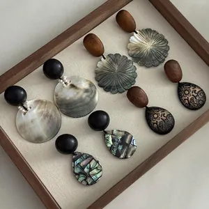 Close-up of assorted niche design shell and wood statement earrings presented in a wooden tray