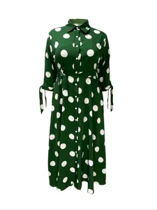 Close-up view of a green long sleeve maxi shirt dress with white polka dot patterns and tie waist