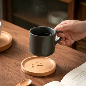Detailed view of a hand holding a ceramic mug over a wooden bear paw coaster.