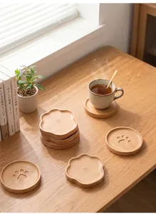 Natural beech wood coasters featuring cute paw and floral designs on a sunny wooden desk.