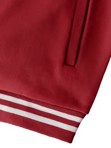 Macro view of red sports jacket showing heavy fabric texture and striped ribbed hem