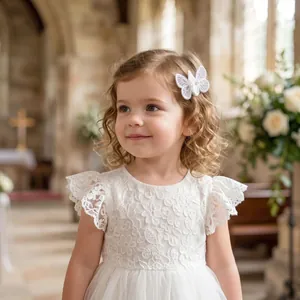 Detalle de una pinza para el pelo de mariposa de encaje blanco con perlas en una niña