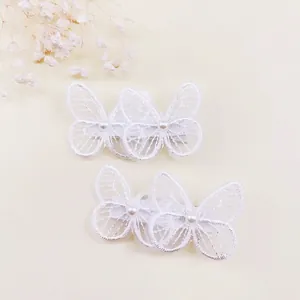 Detalle de pinzas para el pelo de mariposa de encaje blanco bordado con perlas para niñas