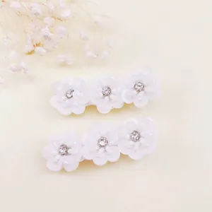 Detalle de dos horquillas de flores blancas con perlas y pedrería