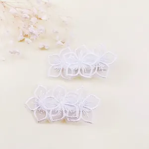 Primer plano de delicadas pinzas para el cabello con flores de encaje bordadas blancas.