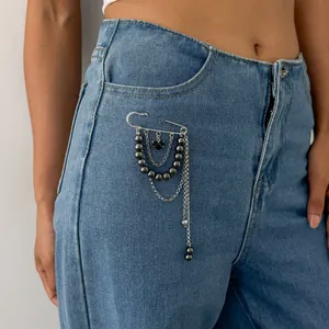Gros plan d'une broche tendance à pompons en perles CCB élégante épinglée sur un jean.