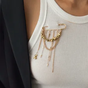 Gros plan d'une broche épingle dorée avec des chaînes pendantes et des perles.