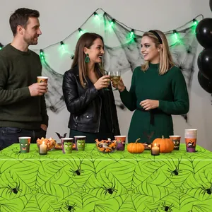 Halloween party scene featuring a vibrant green spider web patterned tablecloth.