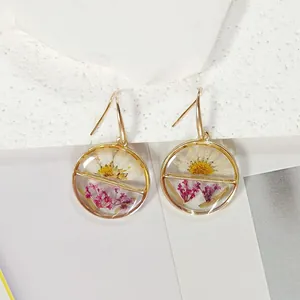 Detailed view of handmade circular resin earrings with real dried daisy flowers