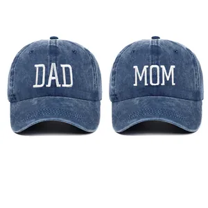 Detailed view of white DAD and MOM embroidery on blue washed cotton baseball caps