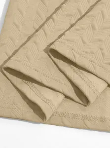 Macro view of beige jacquard knit fabric showing chevron texture and stitching details.