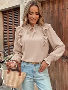 Elegant apricot long sleeve blouse featuring delicate ruffles and tie-neck on model