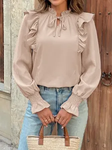 Detailed view of women's elegant ruffled blouse with bow tie neck and elastic cuffs