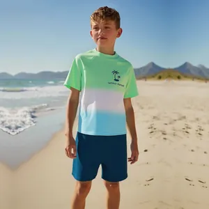 Boys' two-piece swimsuit with green-blue gradient top and navy shorts on sunny beach