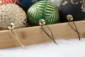 Close-up of textured painted Christmas ball ornaments with gold hanging loops in a wooden tray.